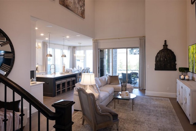 living area with wood finished floors, recessed lighting, stairway, baseboards, and a towering ceiling