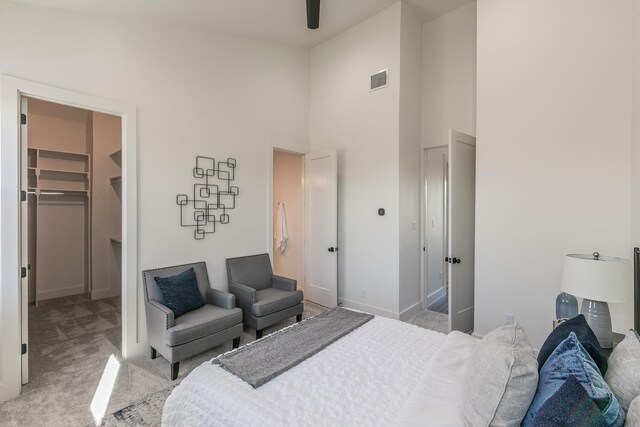 bedroom featuring visible vents, light carpet, a walk in closet, a closet, and a towering ceiling