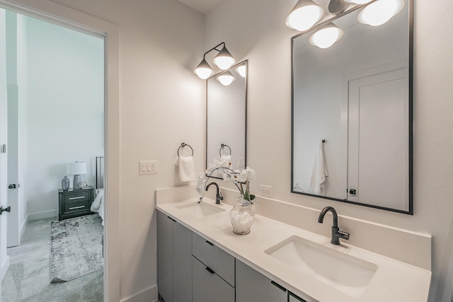 ensuite bathroom featuring double vanity, ensuite bath, baseboards, and a sink