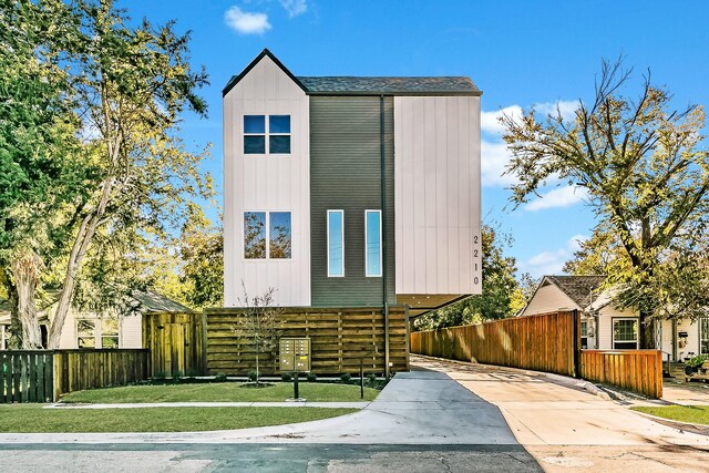 contemporary house featuring board and batten siding, a front yard, and fence