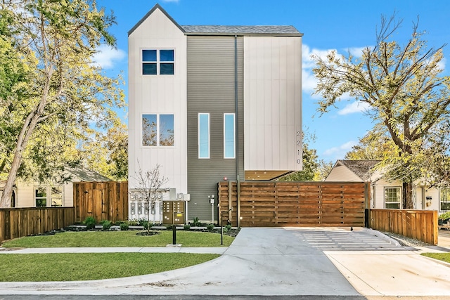 contemporary home with board and batten siding, a front yard, and fence