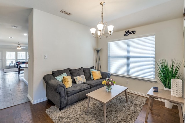 living area with visible vents, ceiling fan with notable chandelier, baseboards, and wood-type flooring