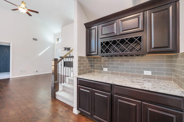 kitchen featuring visible vents, light stone counters, backsplash, dark wood-style floors, and dark brown cabinetry