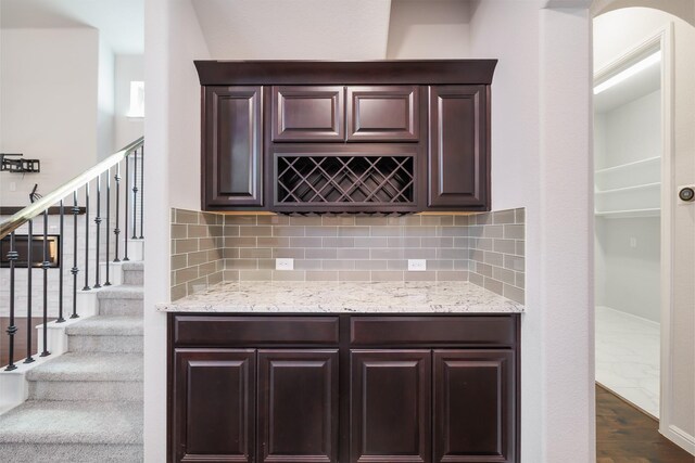 kitchen with decorative backsplash, dark brown cabinetry, and light stone counters