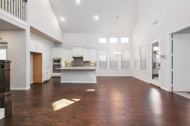 kitchen featuring dark wood-style floors, high vaulted ceiling, stainless steel appliances, white cabinetry, and a chandelier