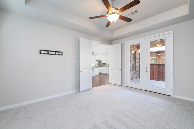 carpeted empty room featuring baseboards, french doors, a raised ceiling, and visible vents