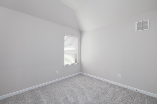 spare room with light carpet, visible vents, baseboards, and lofted ceiling