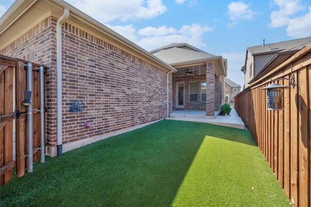 rear view of house featuring a patio, a ceiling fan, a fenced backyard, a lawn, and brick siding