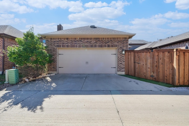 garage with concrete driveway and fence