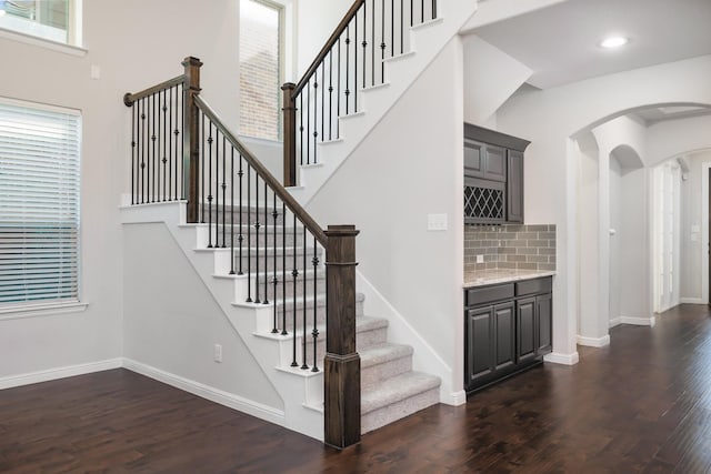 stairway featuring plenty of natural light, wood finished floors, and baseboards