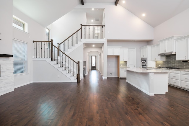 kitchen featuring tasteful backsplash, dark wood finished floors, stainless steel gas cooktop, beam ceiling, and white cabinets