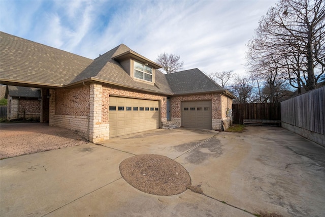 view of home's exterior featuring fence, concrete driveway, an attached garage, a shingled roof, and brick siding