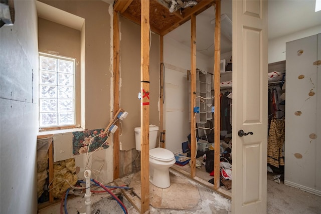 bathroom with a walk in closet and toilet