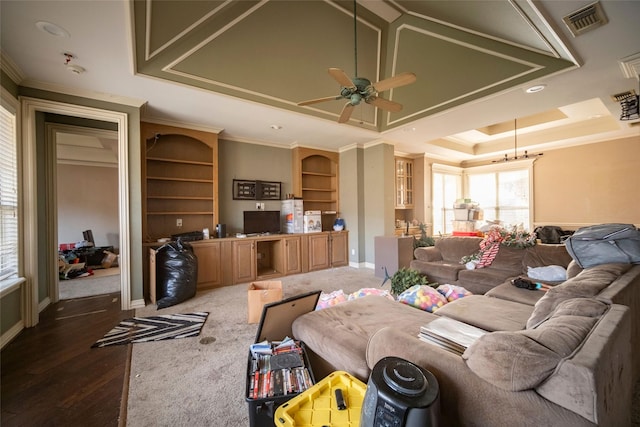 living room with visible vents, ornamental molding, a ceiling fan, wood finished floors, and a raised ceiling