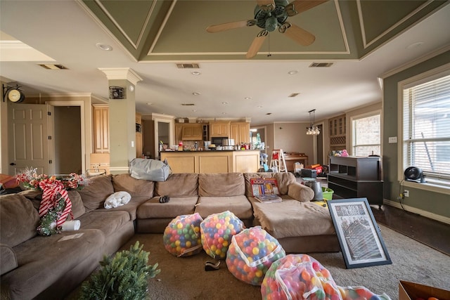 living area with visible vents, crown molding, and a ceiling fan