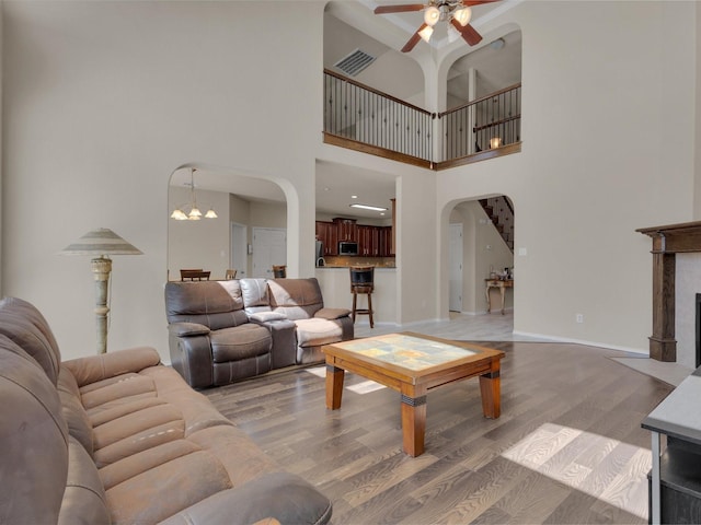 living room featuring visible vents, baseboards, light wood-style flooring, a fireplace with flush hearth, and arched walkways