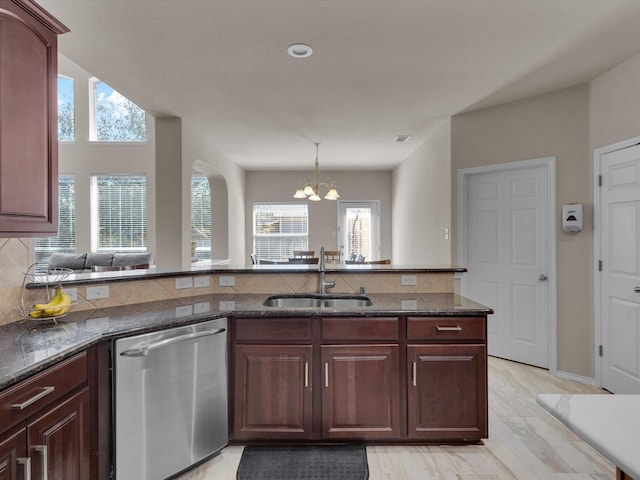 kitchen featuring a sink, dark stone countertops, tasteful backsplash, a peninsula, and dishwasher