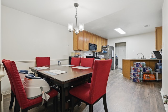 dining area with a notable chandelier, washer / dryer, visible vents, and wood finished floors