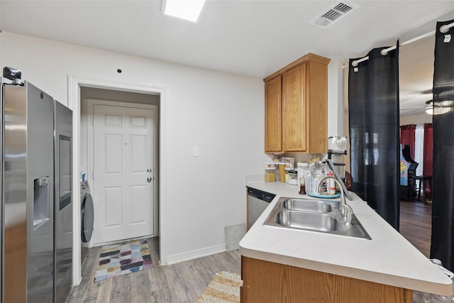 kitchen featuring light wood finished floors, visible vents, light countertops, stainless steel appliances, and a sink