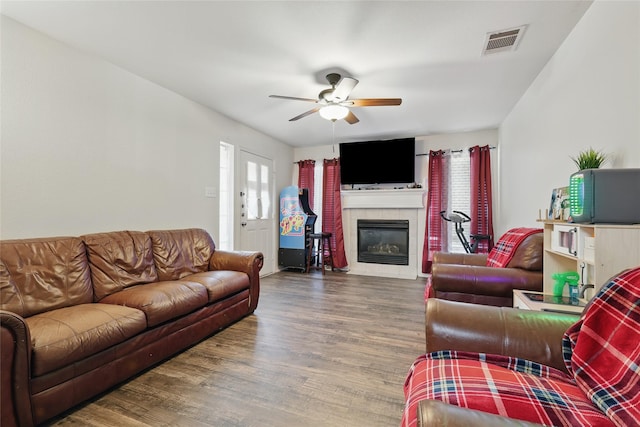 living room featuring visible vents, a fireplace, a ceiling fan, and wood finished floors