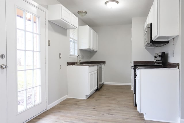 kitchen featuring dark countertops, appliances with stainless steel finishes, white cabinetry, and a sink