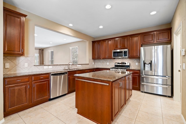 kitchen with a sink, appliances with stainless steel finishes, a center island, and light tile patterned floors