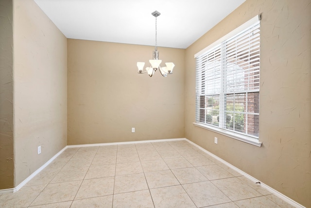 spare room featuring an inviting chandelier, light tile patterned floors, and baseboards