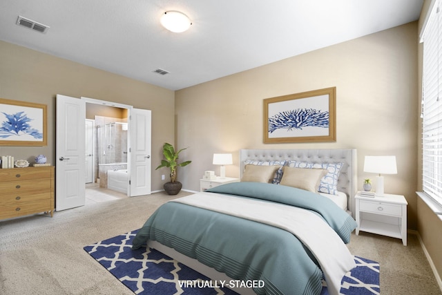 carpeted bedroom with visible vents, ensuite bath, and baseboards