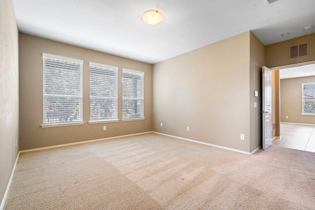 spare room with baseboards, visible vents, and carpet floors