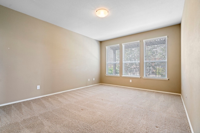 unfurnished room with carpet flooring and baseboards