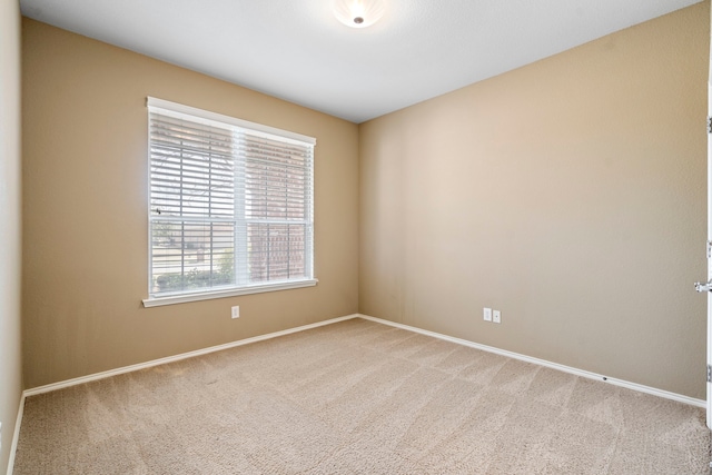 spare room with baseboards and light carpet