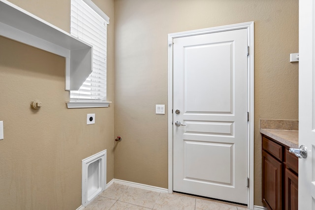 clothes washing area with electric dryer hookup, baseboards, light tile patterned flooring, and laundry area