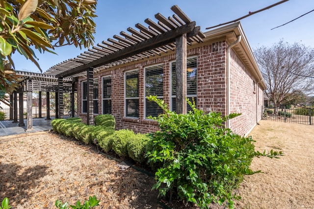 view of property exterior with a pergola, fence, and brick siding