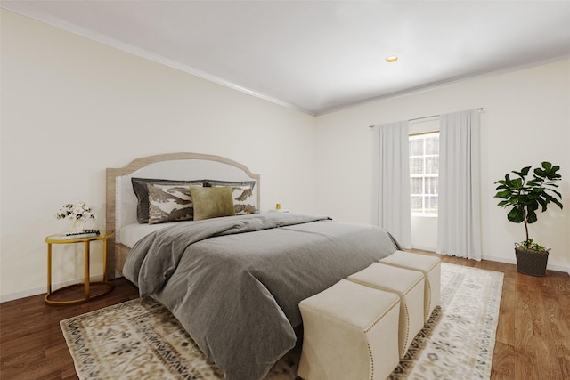 bedroom with baseboards, wood finished floors, and ornamental molding