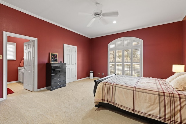 bedroom featuring a ceiling fan, ensuite bath, carpet flooring, crown molding, and baseboards