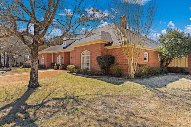 view of front of property with a front lawn, brick siding, and a chimney