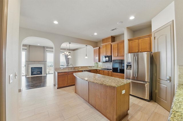 kitchen with tasteful backsplash, visible vents, light stone countertops, a peninsula, and black appliances