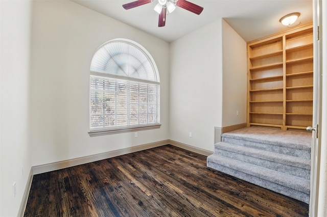 unfurnished room featuring built in features, baseboards, dark wood-type flooring, and ceiling fan