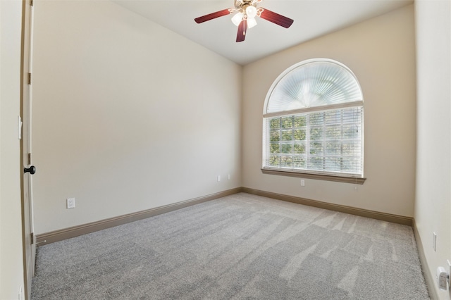 empty room featuring light colored carpet, a ceiling fan, and baseboards