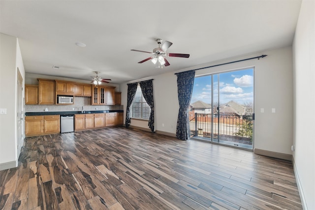 kitchen with ceiling fan, dark wood-type flooring, dishwasher, dark countertops, and tasteful backsplash