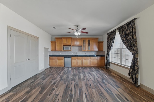 kitchen featuring dark countertops, visible vents, tasteful backsplash, dark wood-type flooring, and stainless steel dishwasher