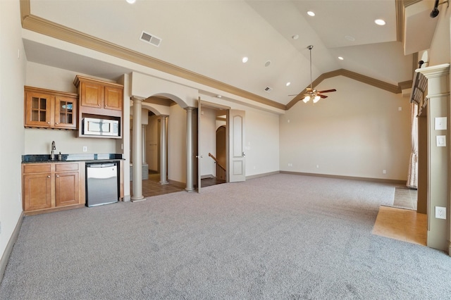 kitchen featuring visible vents, brown cabinetry, dishwasher, light carpet, and arched walkways