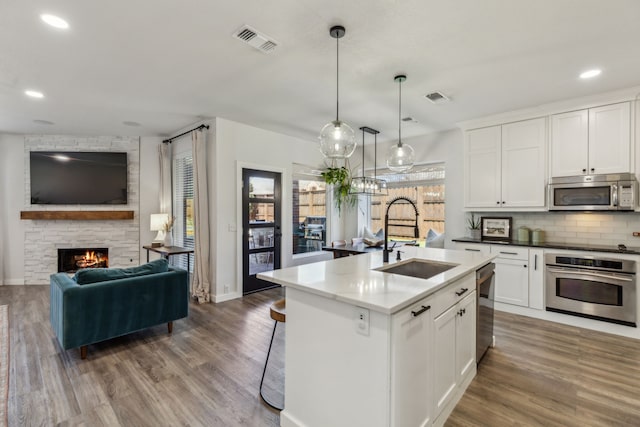 kitchen featuring visible vents, a sink, stainless steel appliances, open floor plan, and backsplash