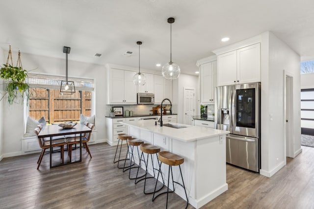 kitchen featuring a sink, tasteful backsplash, appliances with stainless steel finishes, and dark wood-style floors