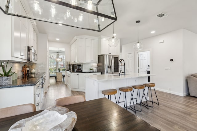 kitchen with decorative backsplash, light wood-style flooring, visible vents, and stainless steel appliances