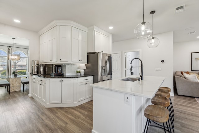 kitchen featuring wood finished floors, stainless steel fridge with ice dispenser, visible vents, and a sink