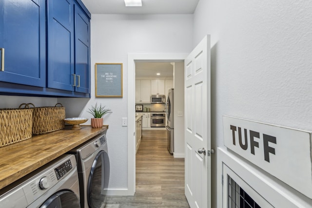 laundry room with cabinet space, wood finished floors, independent washer and dryer, and baseboards