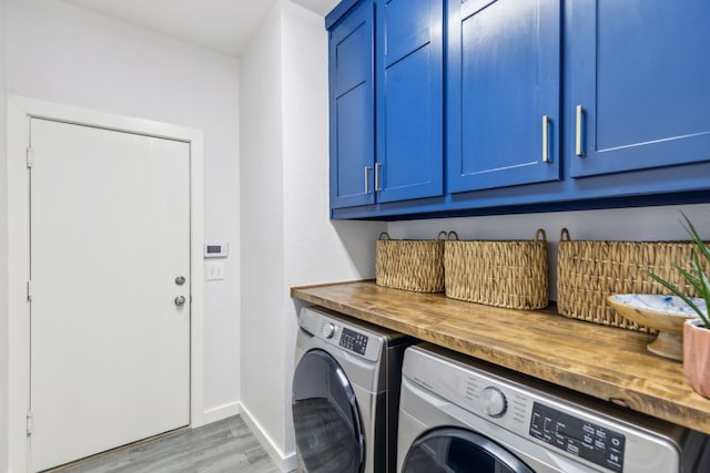 clothes washing area with light wood-type flooring, cabinet space, separate washer and dryer, and baseboards