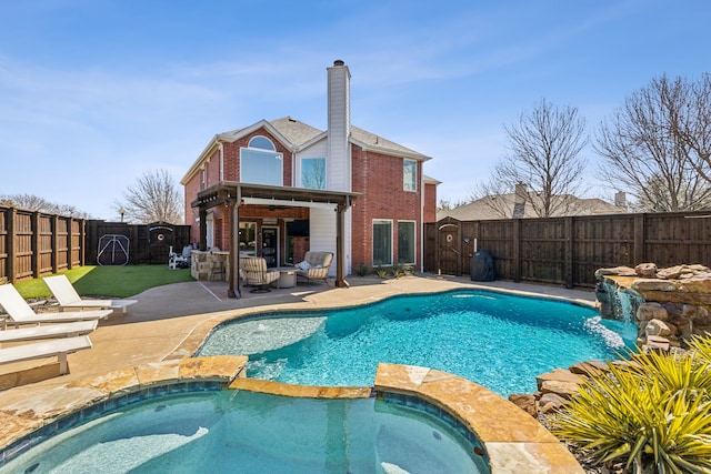 view of swimming pool with a patio, a fenced backyard, a pool with connected hot tub, and ceiling fan