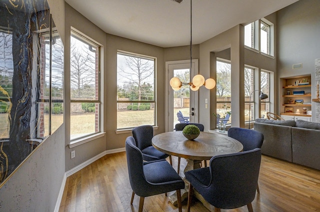 dining space featuring visible vents, built in features, wood finished floors, and baseboards